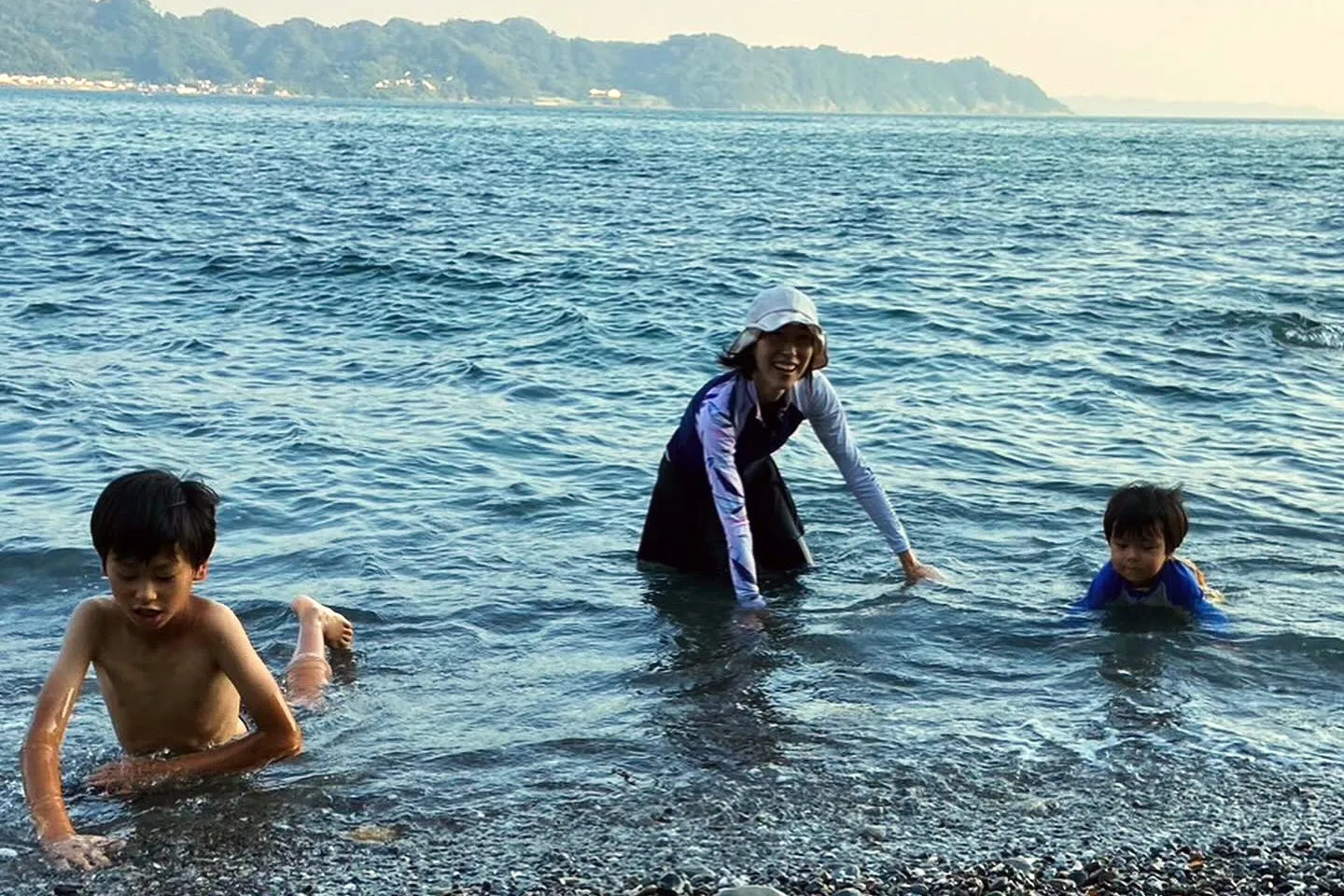 【海に入って遊ぶ長男と次男と真由子さん】