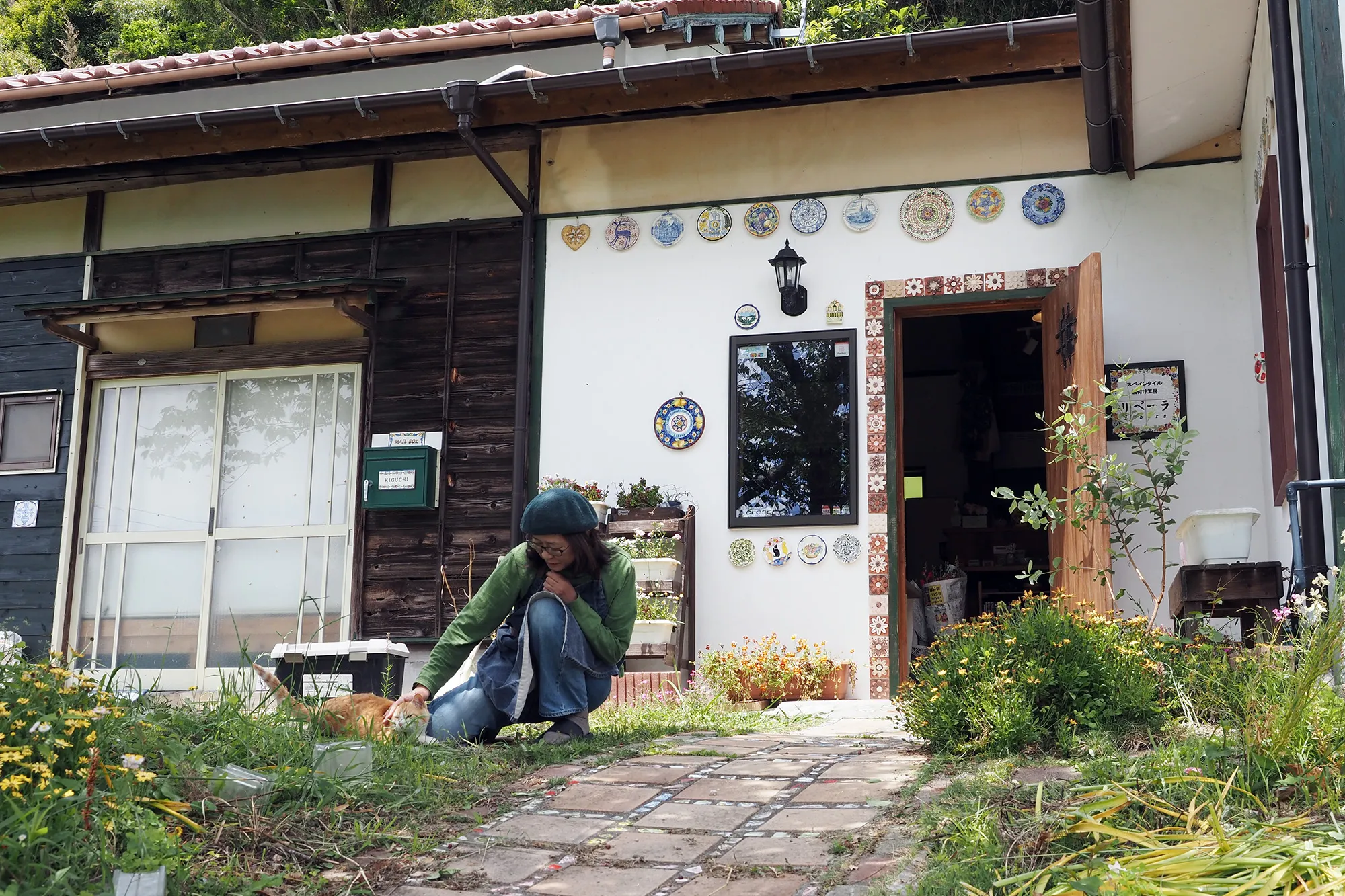 【庭先で猫と遊ぶ樋口さん】
