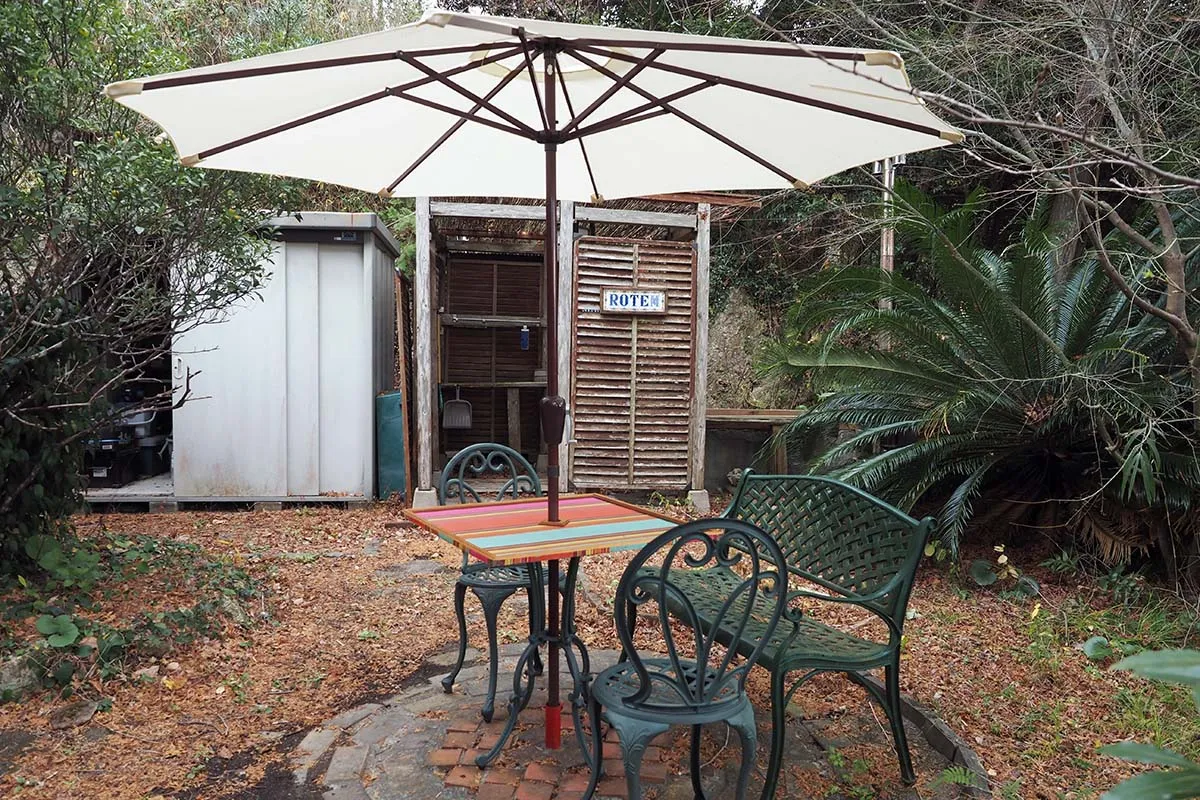 【パラソルの向こう側に脱衣所とサウナ、右手に露天風呂が】