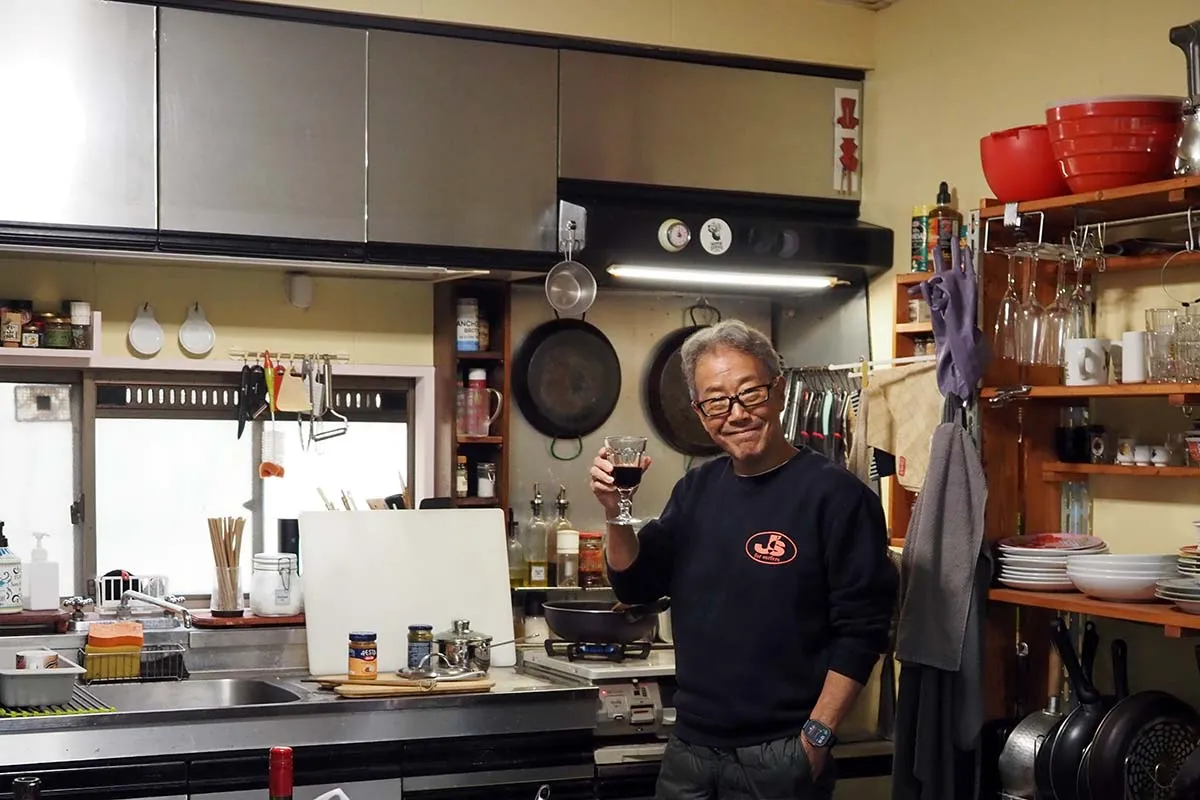 【ワイングラス片手に料理をする酒井さん】