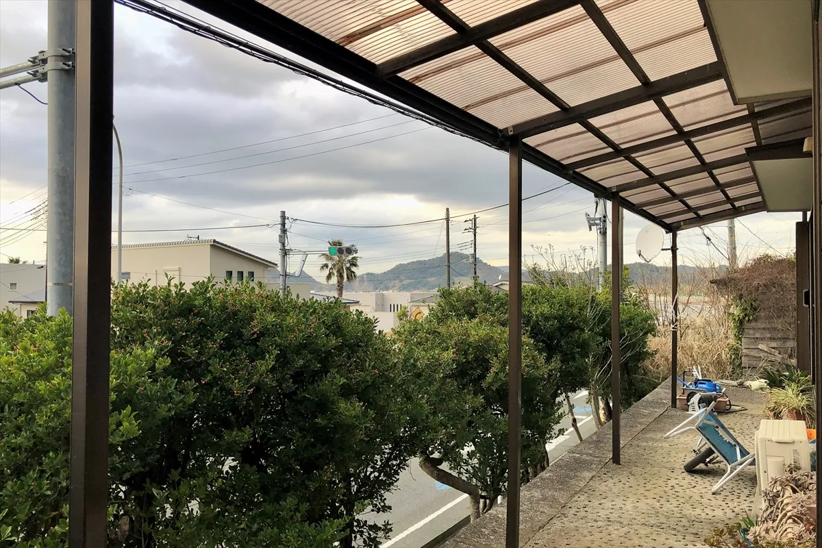 【軒下。道路の向こうに海が見える】