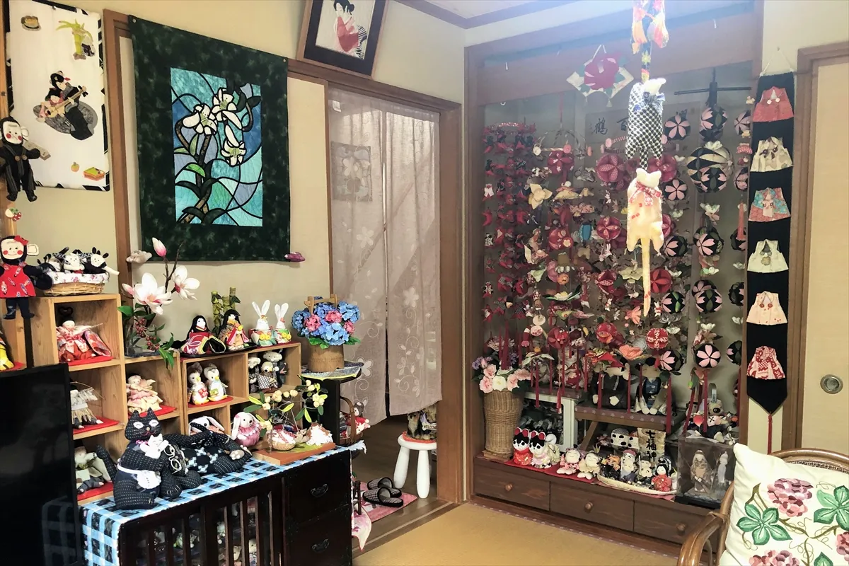 【パッチワークキルト、つるし雛、人形、ぬいぐるみが並ぶ】